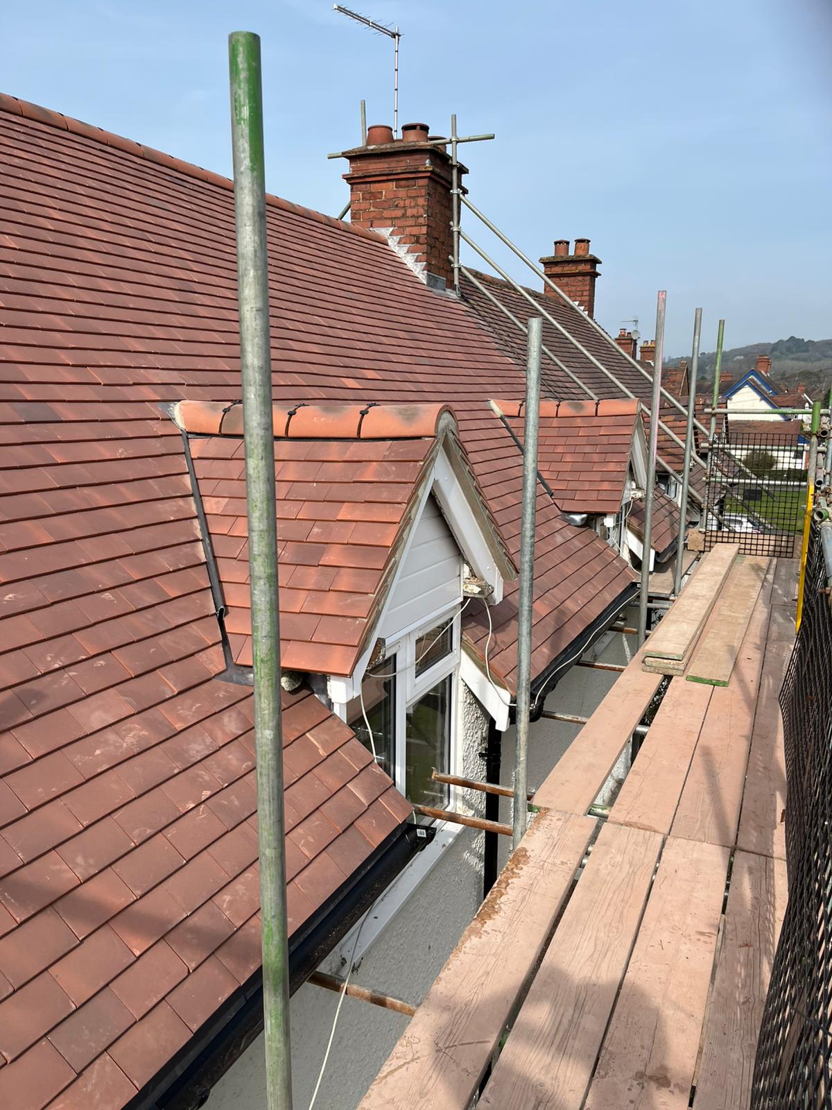 Completed re-roof with fresh terracotta tiles around a dormer window